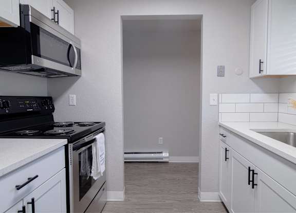 A kitchen with white cabinets and a black stove top oven.