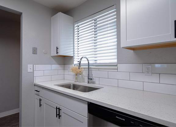 A kitchen with white cabinets and a black dishwasher.