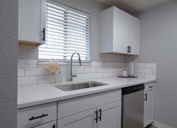 A kitchen with white cabinets and a stainless steel dishwasher.