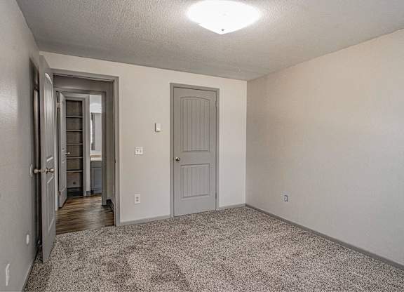A room with a carpeted floor and a door on the right.