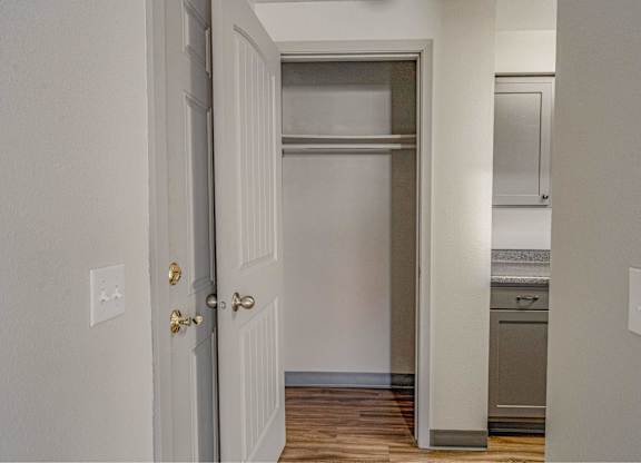 A white door with a gold handle is open to a kitchen.