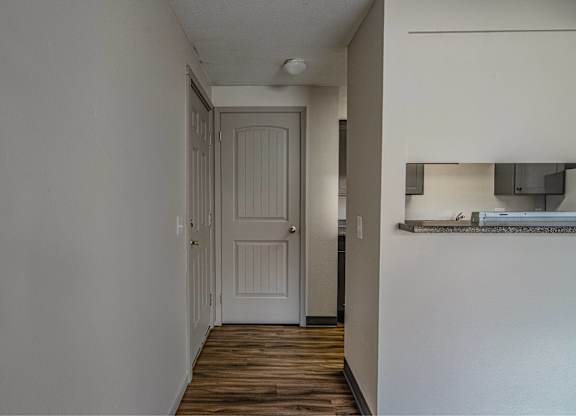 A white door is in a hallway with wood floors.