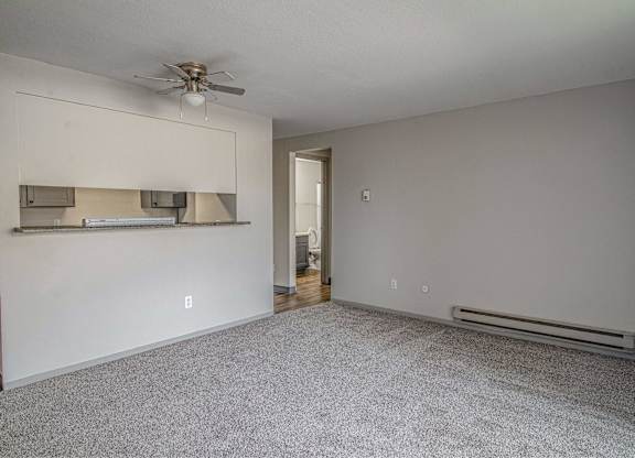 A room with a ceiling fan and a wall-mounted shelf.