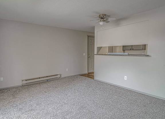Empty room with a ceiling fan and a radiator on the wall.