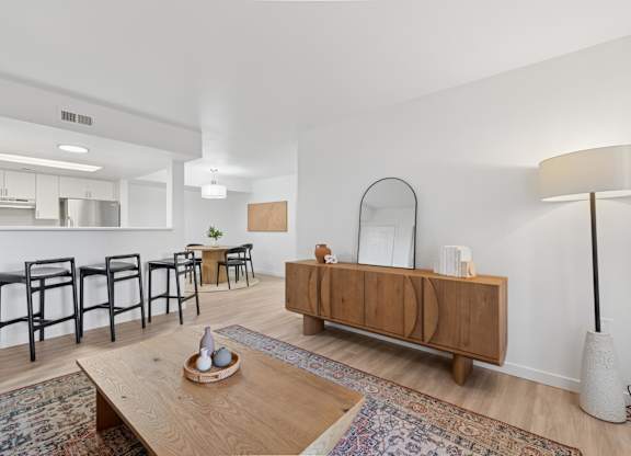 A modern living room with a wooden coffee table and a mirror on the wall.