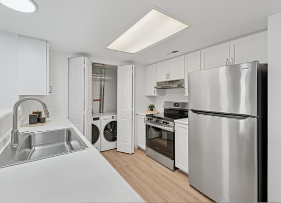 A modern kitchen with a stainless steel refrigerator, sink, and oven.