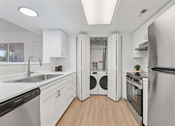 A modern kitchen with white cabinets and stainless steel appliances.