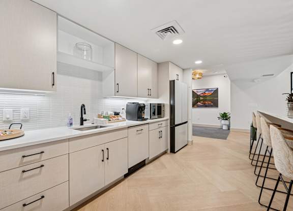 A kitchen with white cabinets and a black fridge.