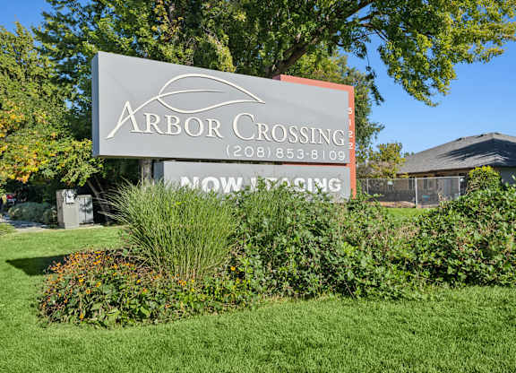 A sign for Arbor Crossing subdivision is displayed in front of a house.