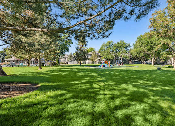 A park with a playground and houses in the background.