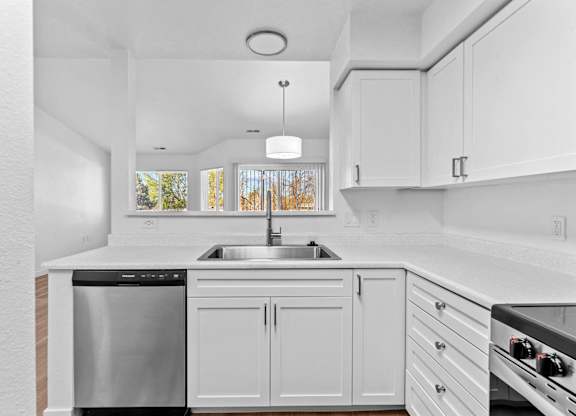 A modern kitchen with white cabinets and stainless steel appliances.