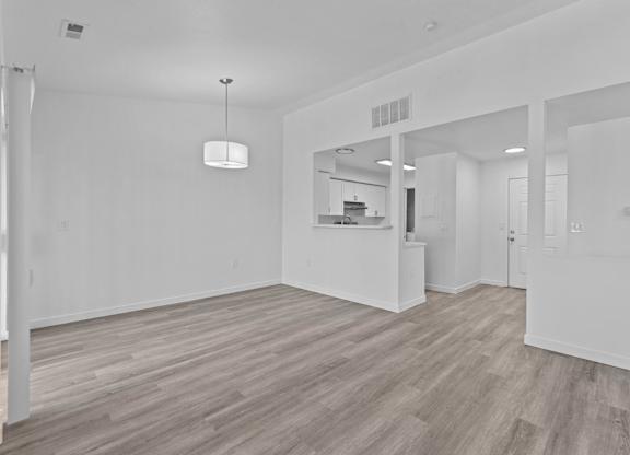 A spacious room with wooden flooring and white walls.