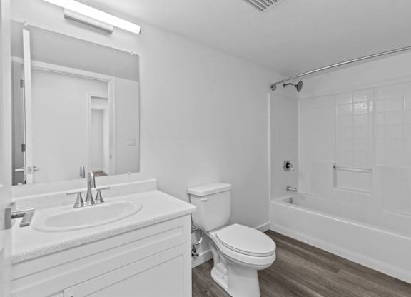 A white bathroom with a toilet, sink, and bathtub.