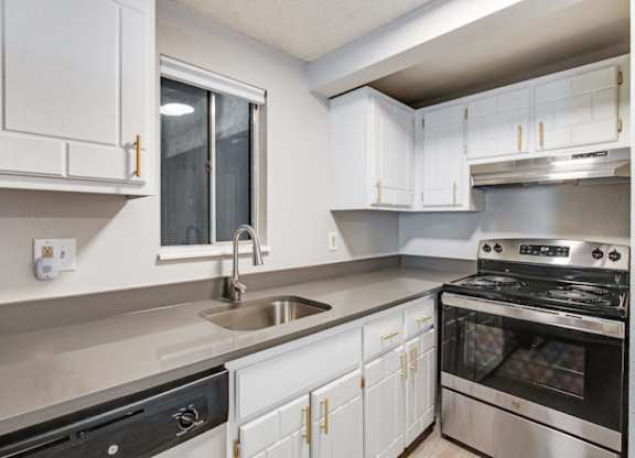 A modern kitchen with white cabinets and stainless steel appliances.