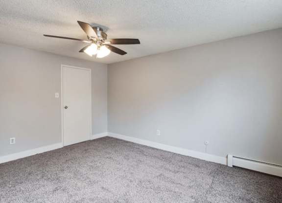 A room with a ceiling fan and carpeted floor.