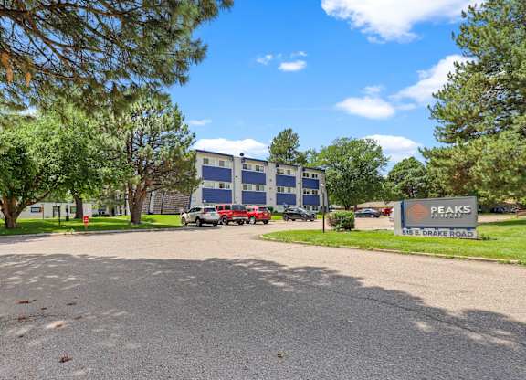 A parking lot with a building and a sign that says Peaks.