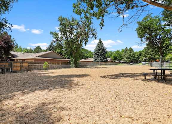 A backyard with a picnic table and a fence.