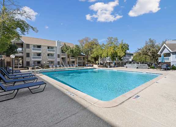 Large swimming pool with sun deck and lounge seating at Polo Club Apartments, Texas
