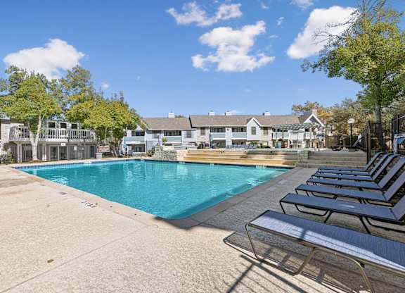 Pool deck with lounge chairs and residential backdrop at Polo Club Apartments, Texas, 78729