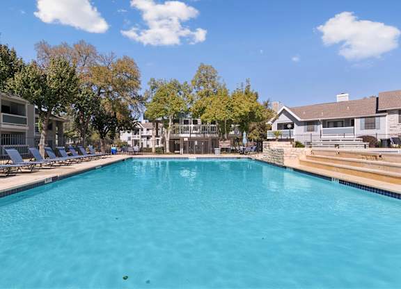 Swimming pool with tiered deck and mature trees at Polo Club Apartments, Austin, TX