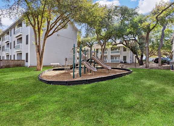 Childrens play area surrounded by green lawn at Polo Club Apartments, Austin