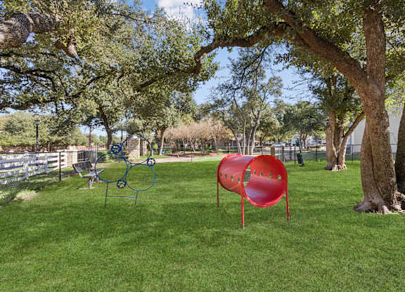 Dog park with agility equipment and shaded trees at Polo Club Apartments, Austin, Texas