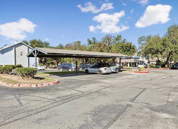 Covered carport parking area with multiple vehicles at Polo Club Apartments, Austin, TX