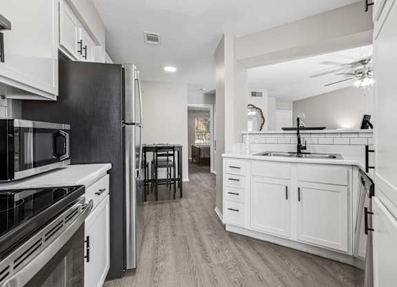 Galley style kitchen with white cabinetry and black fixtures at Polo Club Apartments, Austin