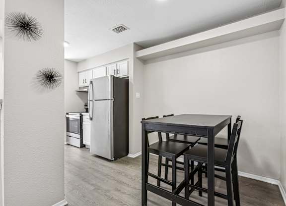 Dining area with black pub table and kitchen view at Polo Club Apartments, Austin, Texas