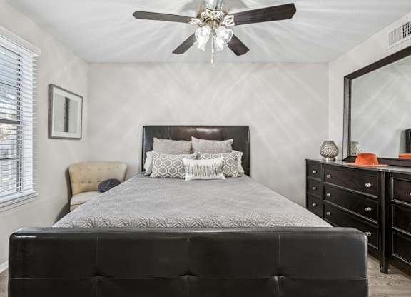 Bedroom with dark wood furniture and ceiling fan at Polo Club Apartments, Austin