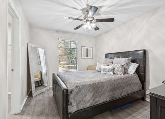 Bedroom with dark leather bed and large mirror at Polo Club Apartments, Texas