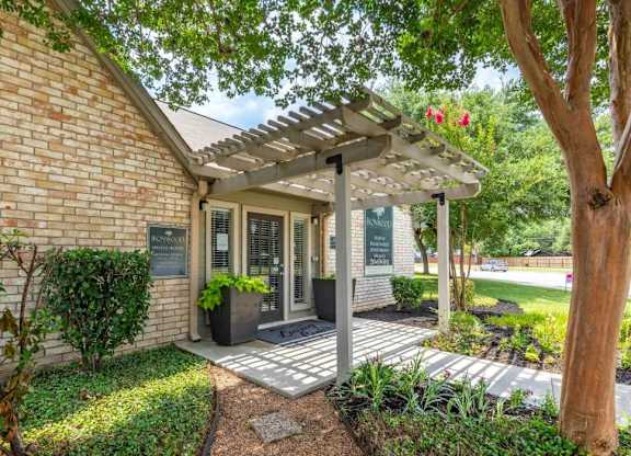 Office building entrance with pergola and garden beds at Peaks at Universal City Apartments, Universal City, TX