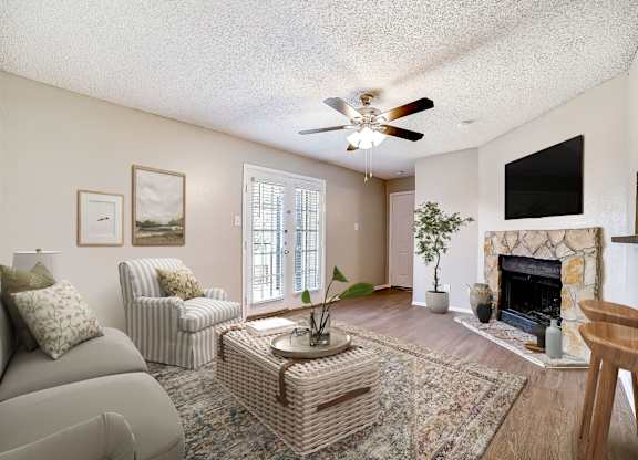 Living room with ceiling fan and stone fireplace at Peaks at Universal City Apartments, Texas, 78148