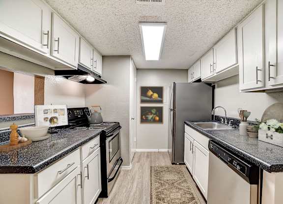 Galley kitchen with white cabinets and stainless steel appliances at Peaks at Universal City Apartments, Texas, 78148