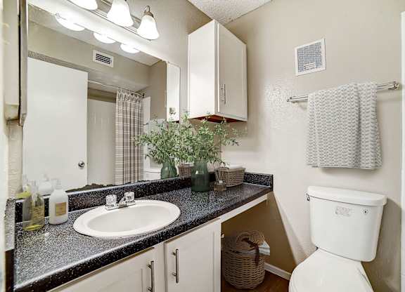 Bathroom with dark granite countertop and white cabinetry at Peaks at Universal City Apartments, Universal City, TX 78148