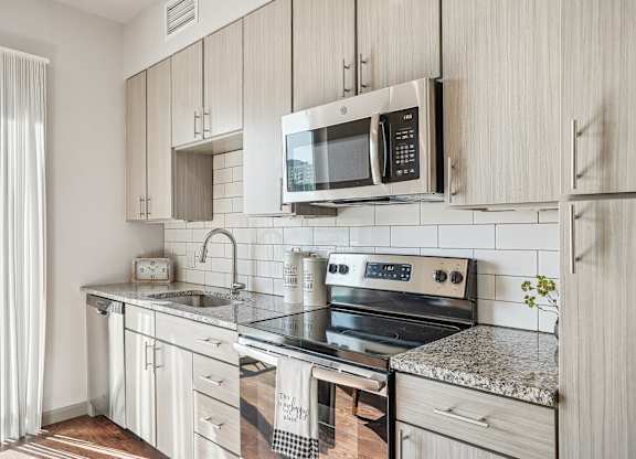 A modern kitchen with a sink, oven, and microwave.