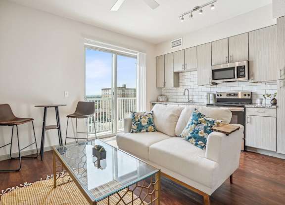 A modern living room with a white couch and a glass coffee table.