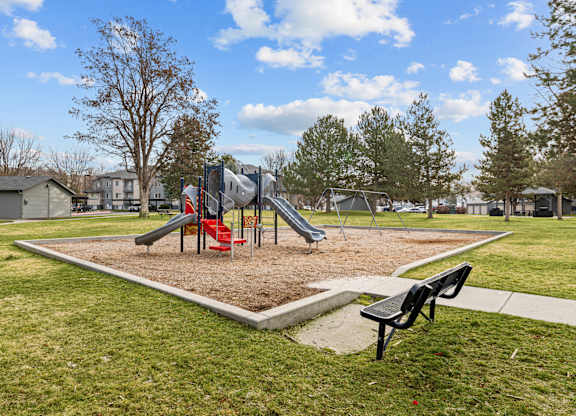 A playground with a slide, swings, and a bench.