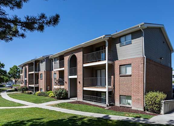 A multi-story apartment building with balconies and a clear blue sky above.