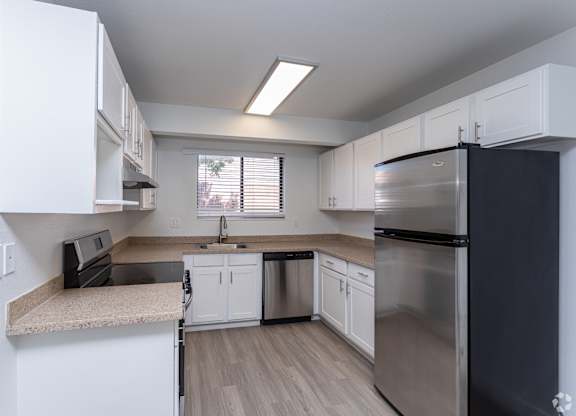 A kitchen with a black refrigerator and white cabinets.