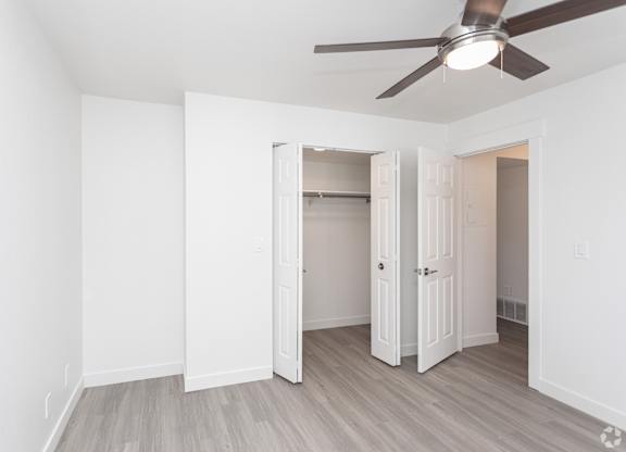 A room with a ceiling fan and a doorway leading to another room.