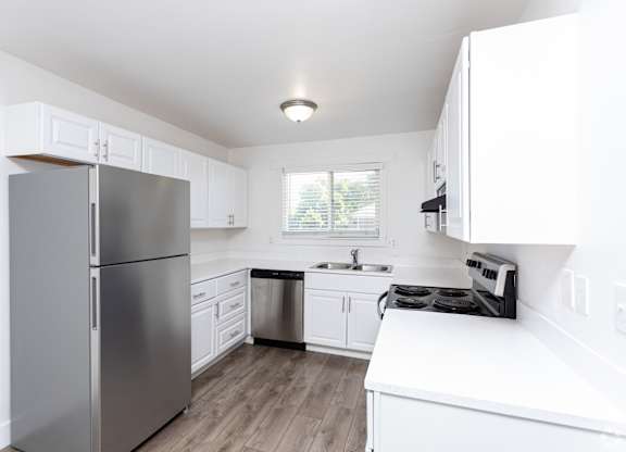 A modern kitchen with a stainless steel refrigerator and white cabinets.