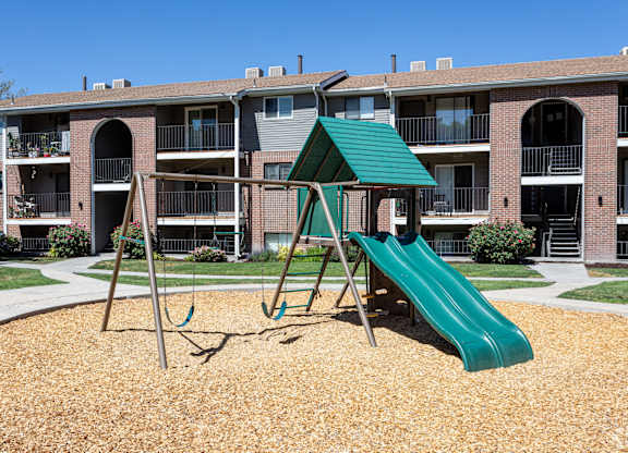 A playground with a green slide and a green roofed structure.