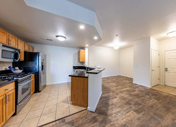 A kitchen with wooden cabinets and a black refrigerator.