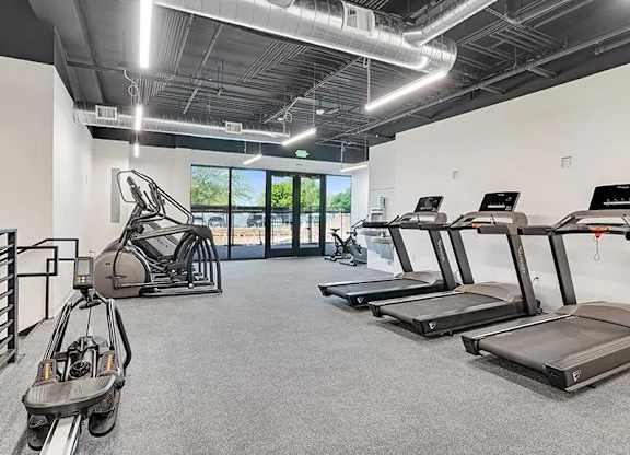 A gym with treadmills and elliptical machines.