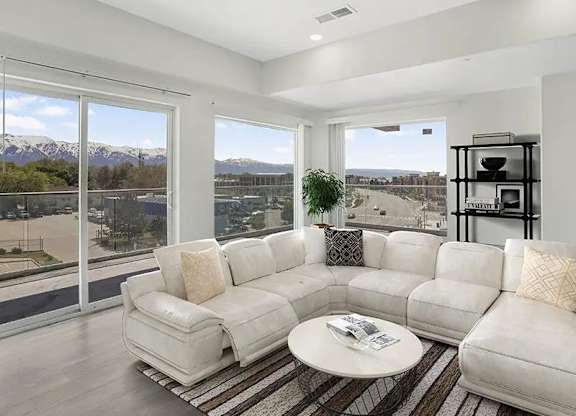 A white couch with a coffee table in front of a window with a view of the mountains.