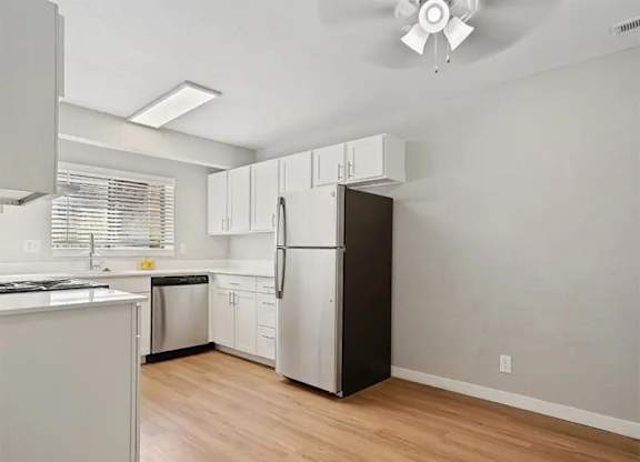 A kitchen with white cabinets and a black refrigerator.