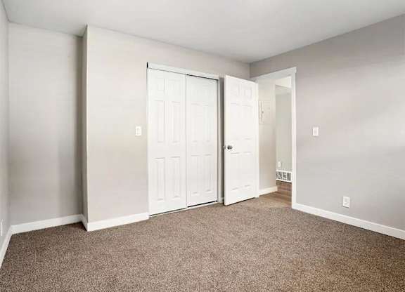 A room with a carpeted floor and two white doors.