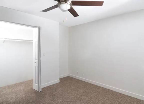 A room with a ceiling fan and carpeted floor.