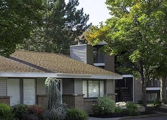 A house with a brown roof and a tree in front.